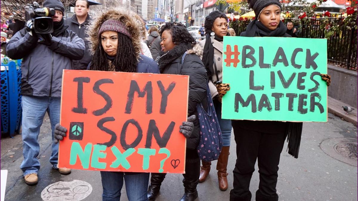 Zwei Frauen streiken mit #blacklivesmatter Schild in den Händen.