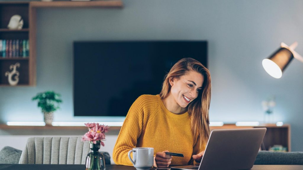 lächelnde Frau beim Online Shopping Zuhause vor dem Laptop