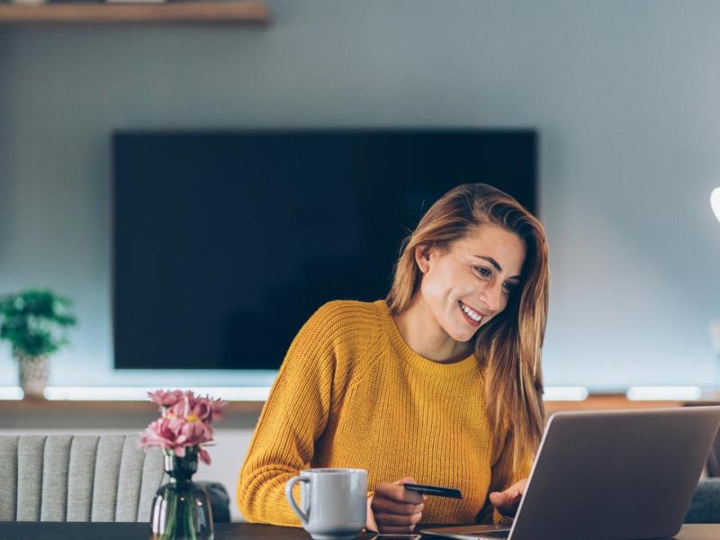 lächelnde Frau beim Online Shopping Zuhause vor dem Laptop