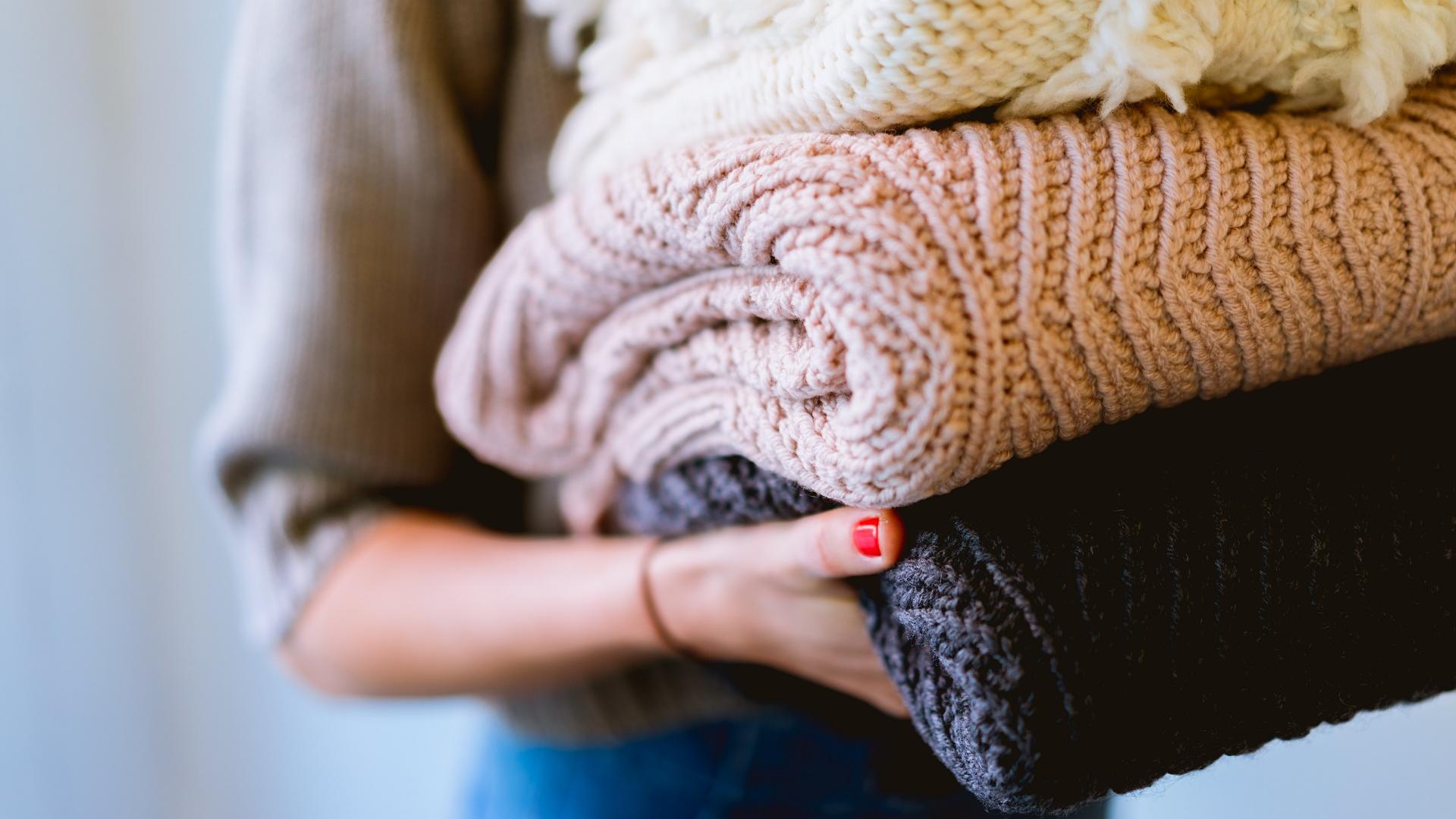 Kleider Spenden: Frau mit Pullovern