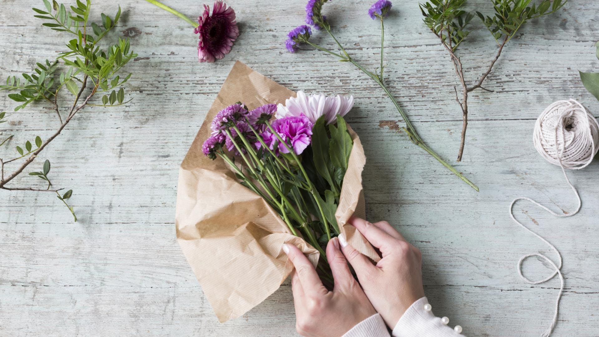 Hands of woman wrapping bunch of flowers