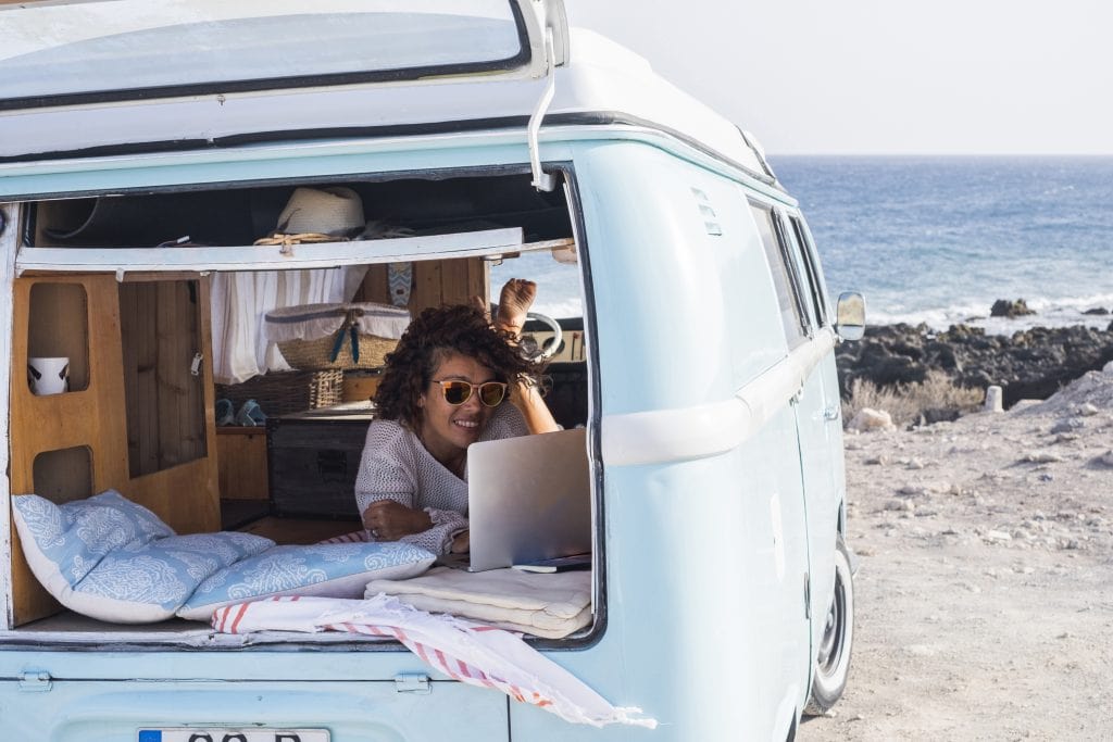 van life camper frau bett laptop strand urlaub reisen