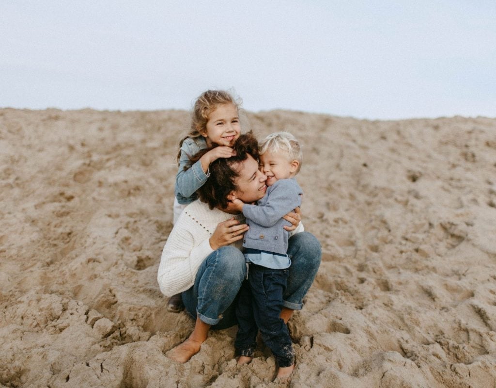 Frau mit Kindern am Strand glücklich happy