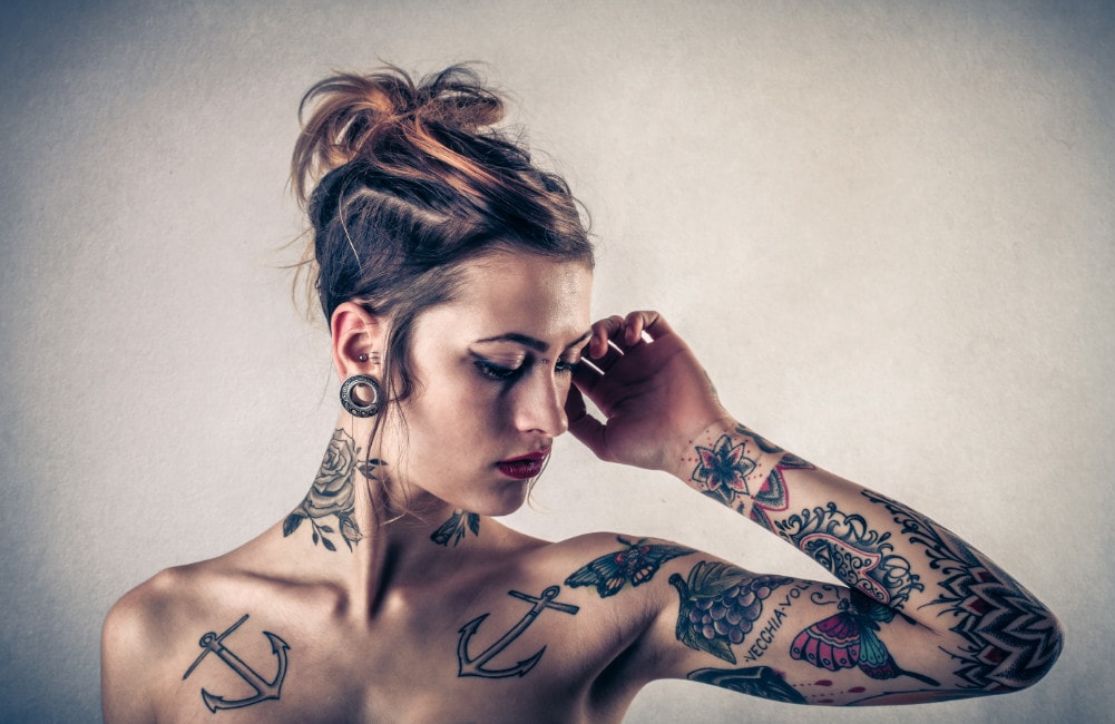 Frau zeigt ihre Tattoos auf ihrem Oberkörper.