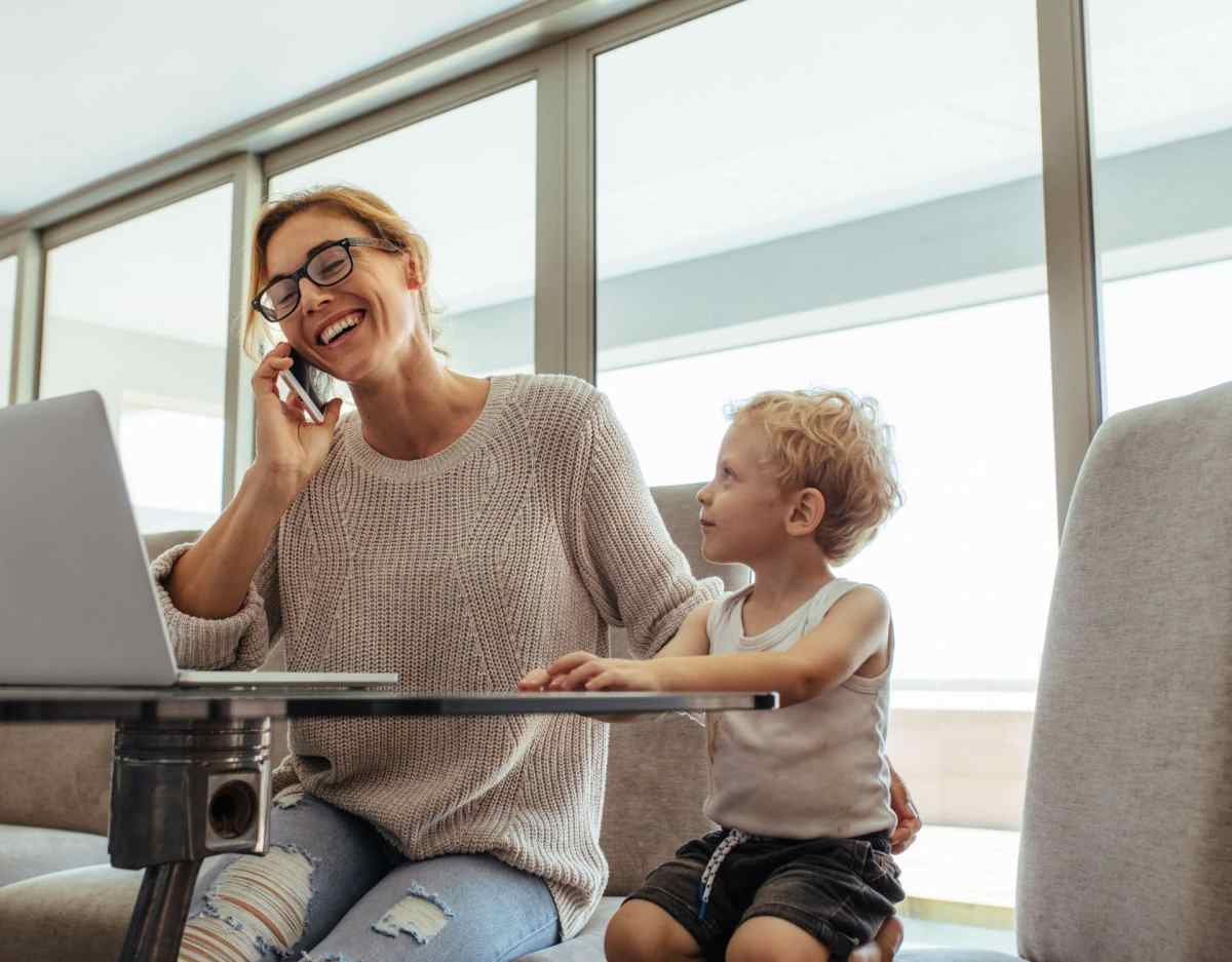 Eine Frau telefoniert. Daneben sitzt ein Kleinkind.