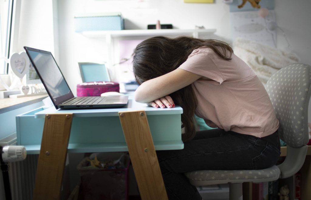 Mädchen traurig am Schreibtisch mit Kopf auf dem Tisch