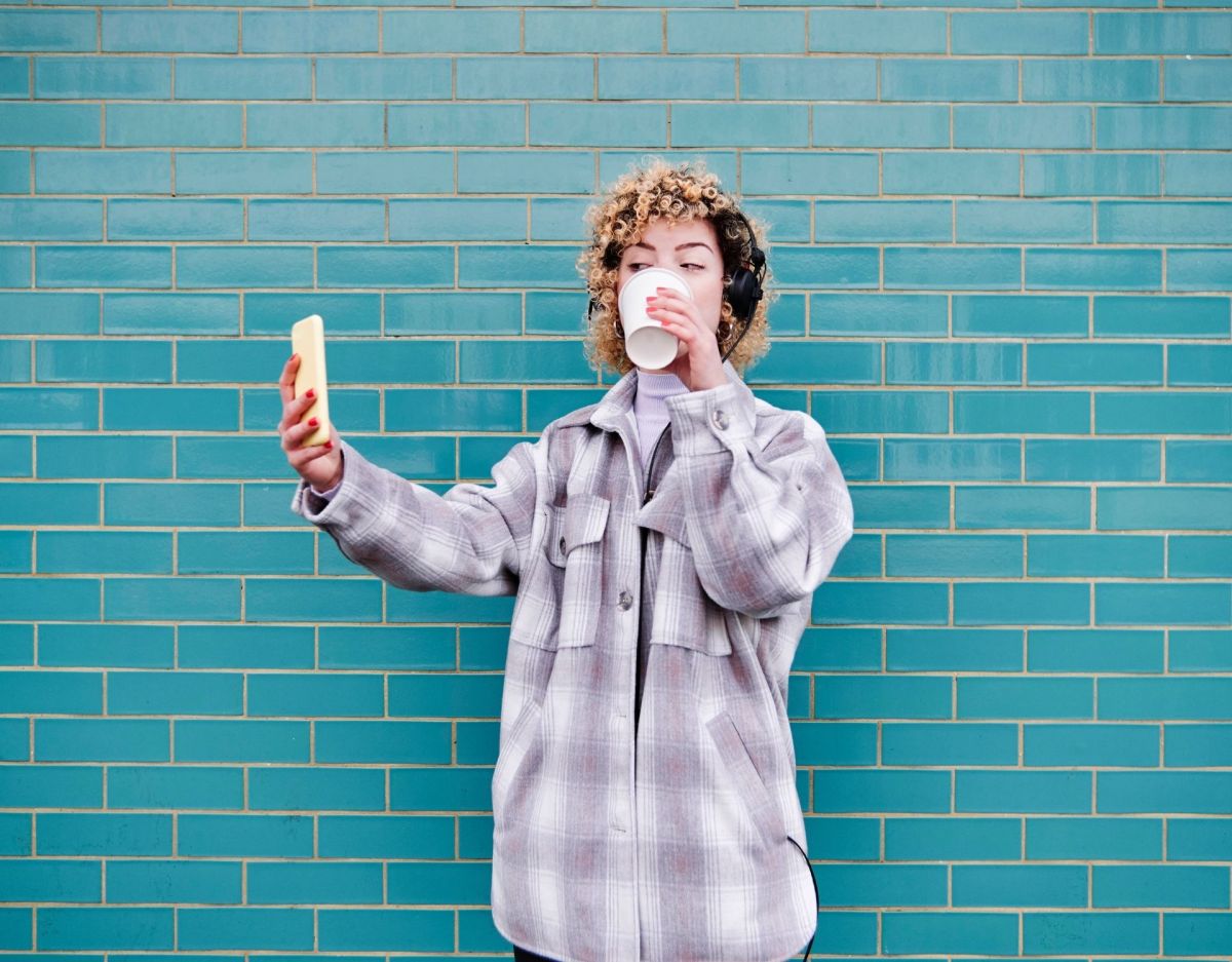 Frau mit Kaffeebecher vor blauer Wand