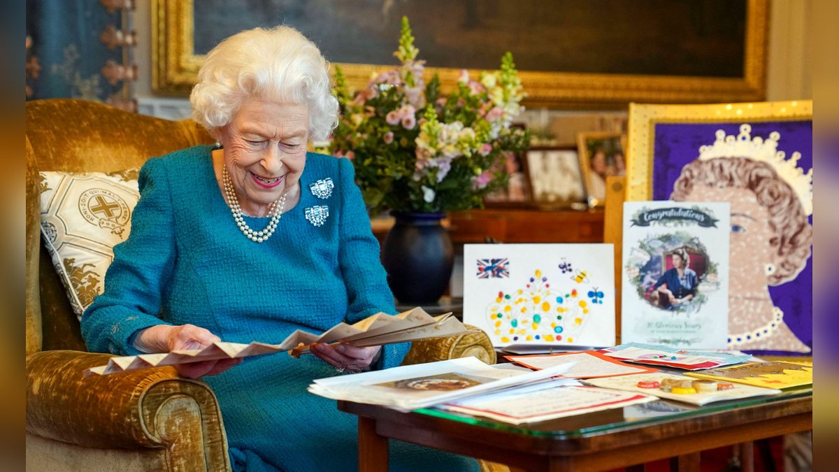 Queen Elizabeth II. amüsiert sich über alte Glückwunschkarten.. © imago images/i Images