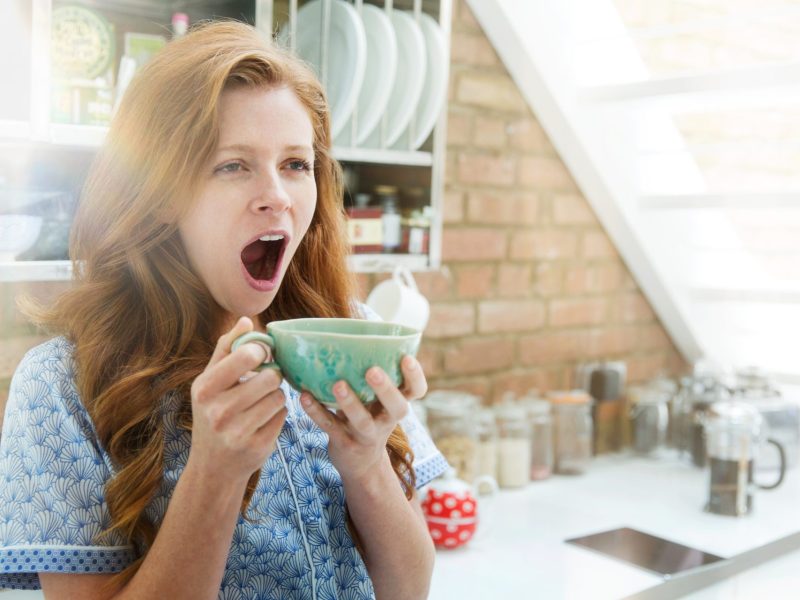 Frau gähnt mit Kaffee