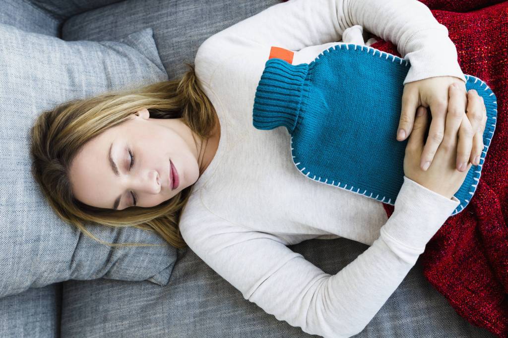 Frau liegt krank auf der Couch