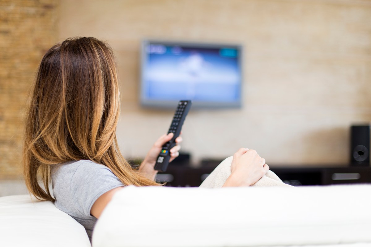 Frau hält Fernsehfernbedienung in der Hand.