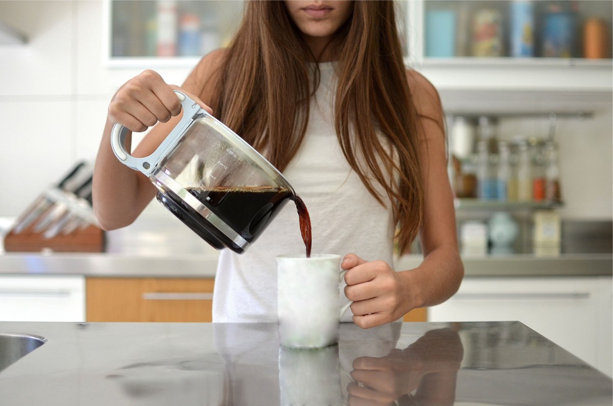 Junge Frau gießt Kaffee in eine Tasse.