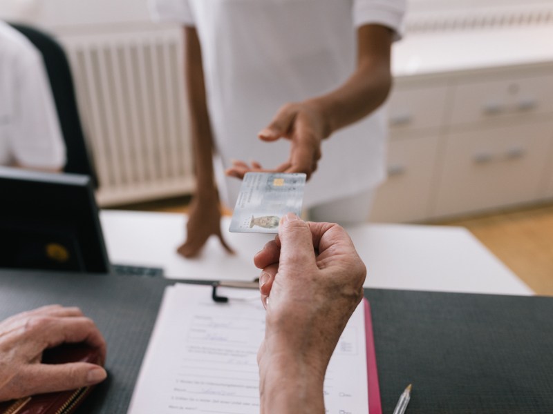 Frau gibt Krankenkassenkarte ab.