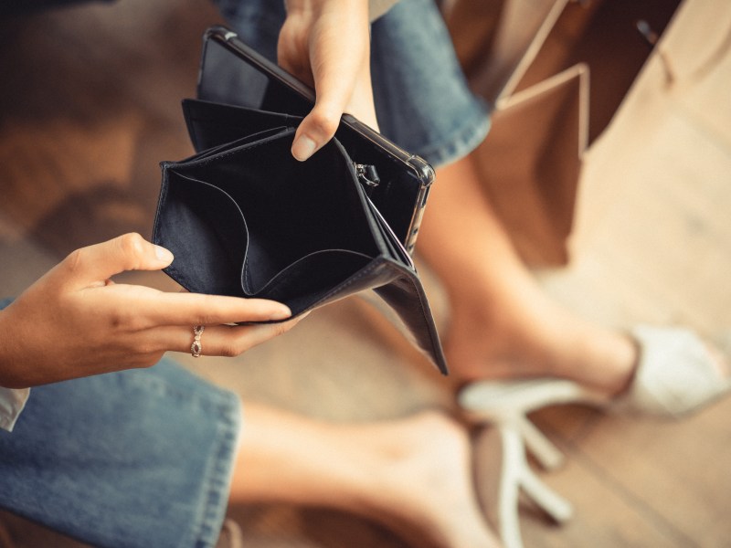 Frau hält leeres Portemonnaie in der Hand.