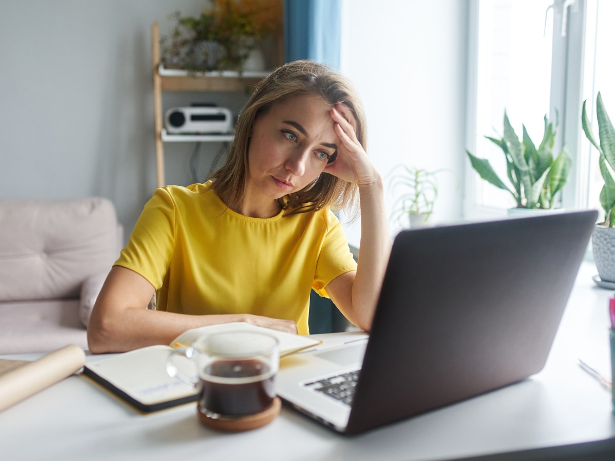 Junge Frau schaut deprimiert auf den Laptop