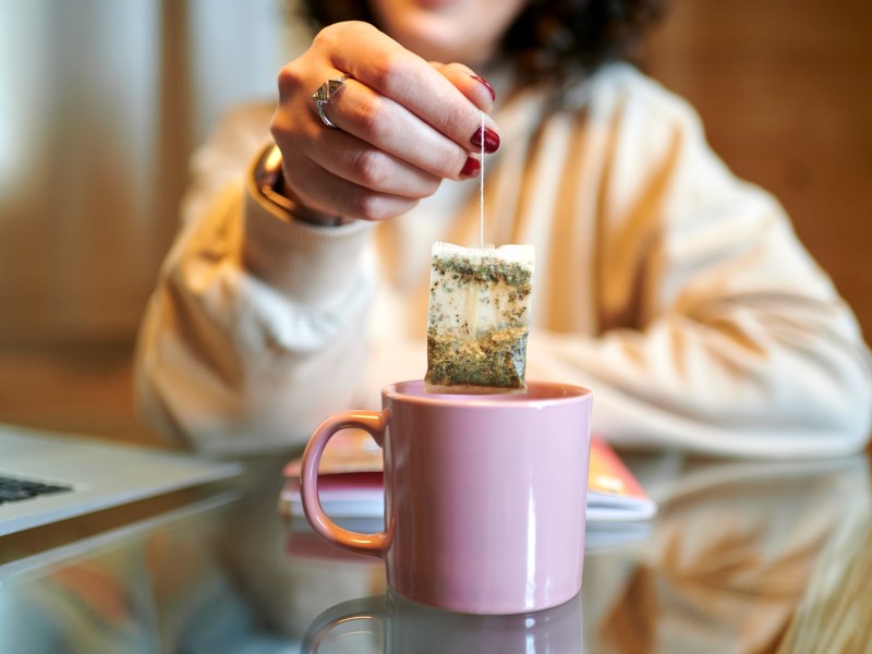 Frau hebt Teebeutel aus der Tasse