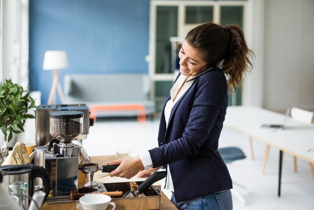 Frau macht sich im Büro einen Kaffee.