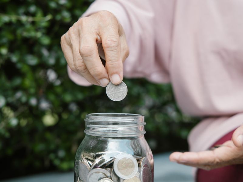 Alte Frau legt Geld in ein Glas