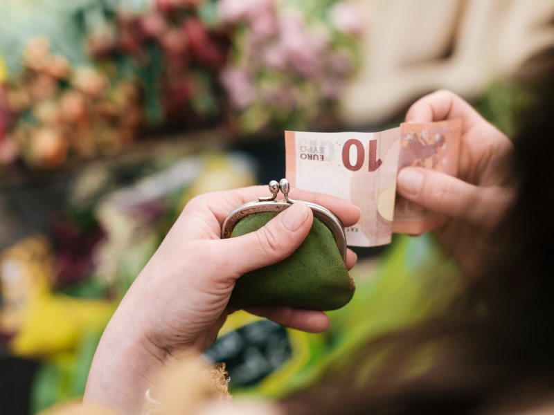 Frau hält einen Geldschein und ihr Portemonnaie in der Hand.