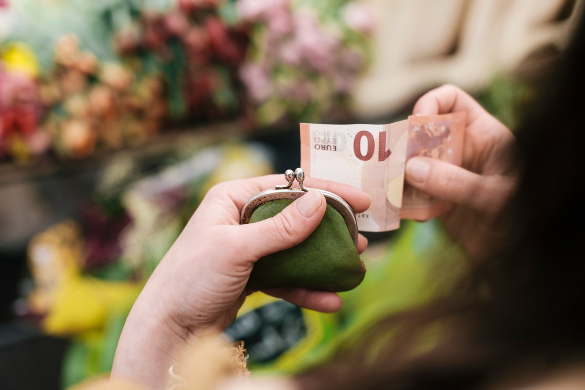 Frau hält einen Geldschein und ihr Portemonnaie in der Hand.