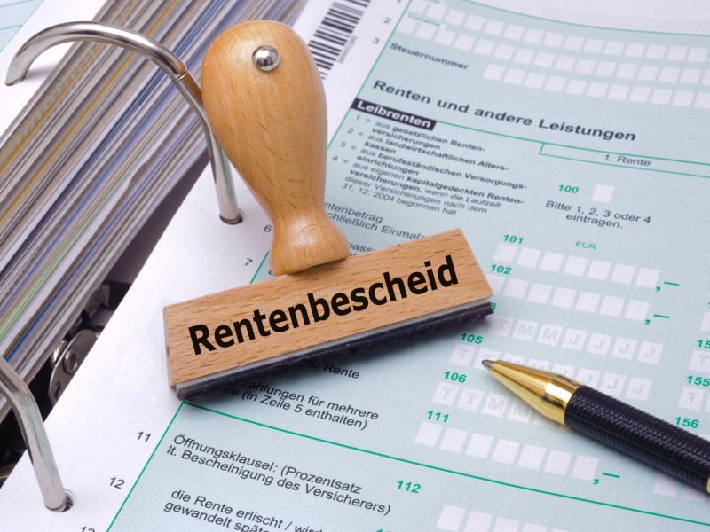 Ein Stempel mit dem Aufdruck "Rentenbescheid" liegt auf einem Rentenantrag.