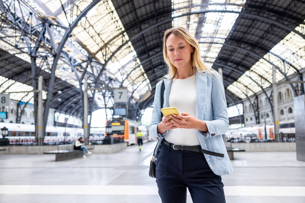 Frau wartet auf Zug Deutschlandticket