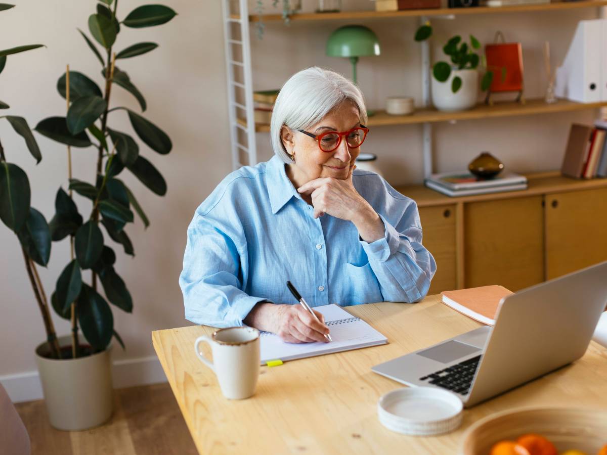 Ältere Dame arbeitet vor dem Laptop.