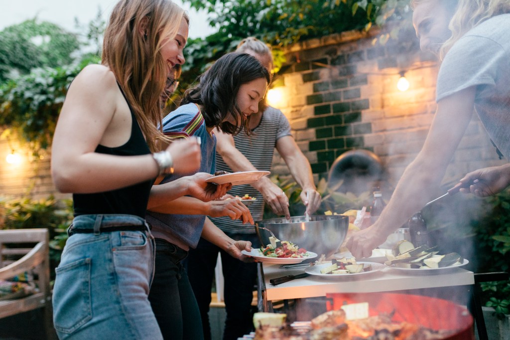 Eine Gruppe junger Leute grillt gemeinsam.