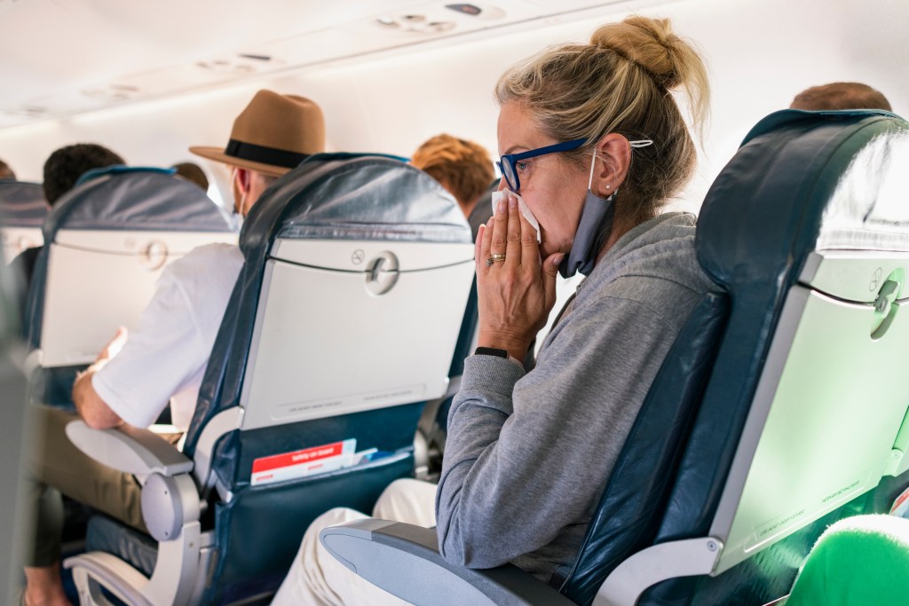 Eine Frau putzt sich im Flugzeug die Nase