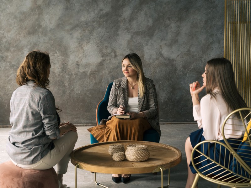 Führungskraft: Drei Geschäftsfrauen unterhalten sich im Büro.