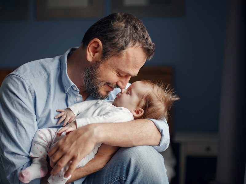 Vater küsst Baby auf den Kopf.