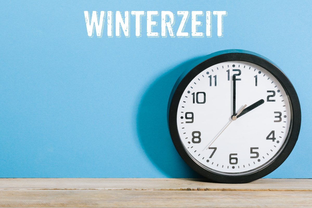 Eine Uhr steht auf einem Tisch. Über ihr steht die Aufschrift: Winterzeit.