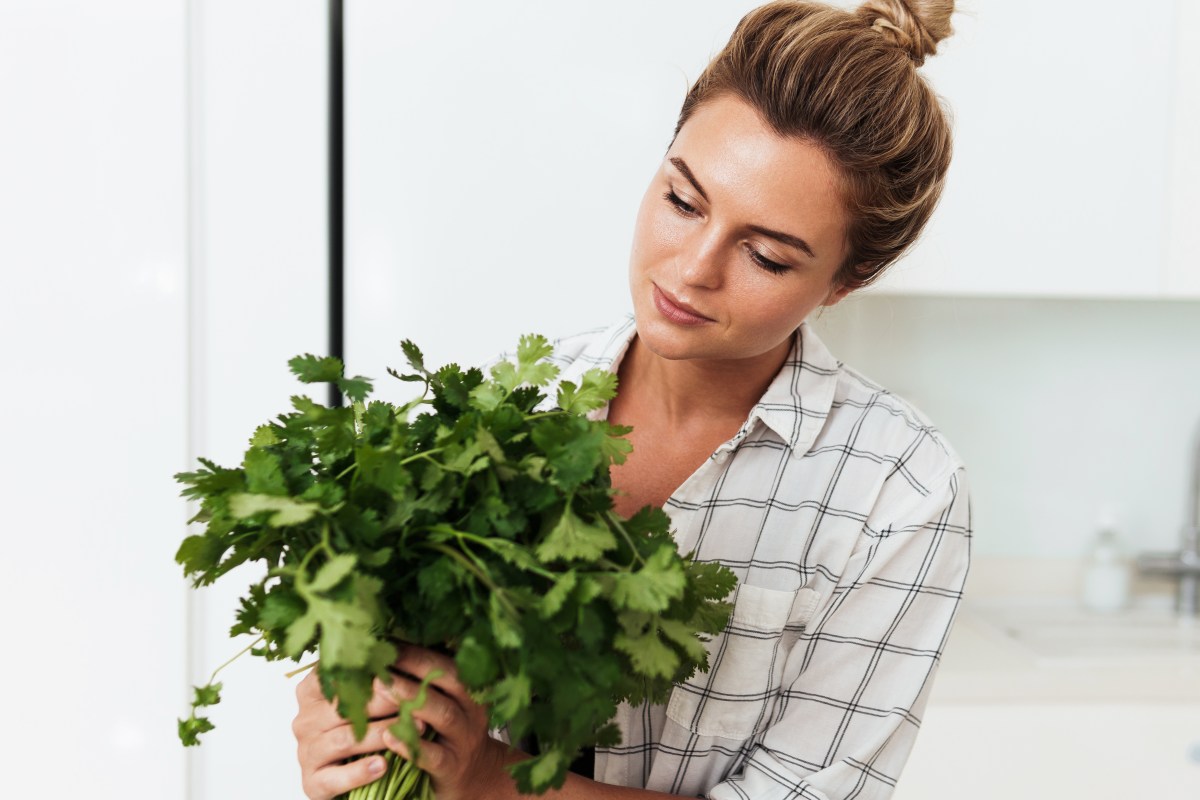 Frau mit Koriander Pflanze: Schmeckt er für dich auch nach Seife? Das ist der Grund