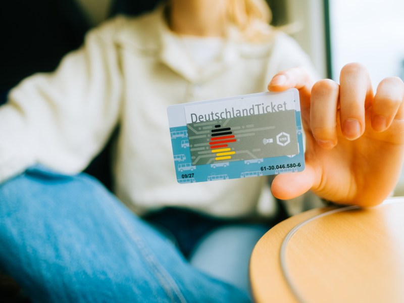 Eine Frau hält das Deutschlandticket in der Hand.