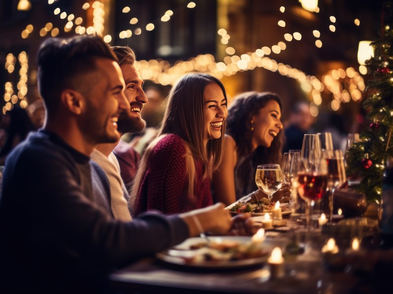 Frauen und Männer sitzen an einem gedeckten Tisch im Restaurant.