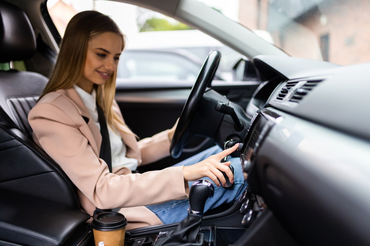 Eine Frau sitzt im Auto und startet es.