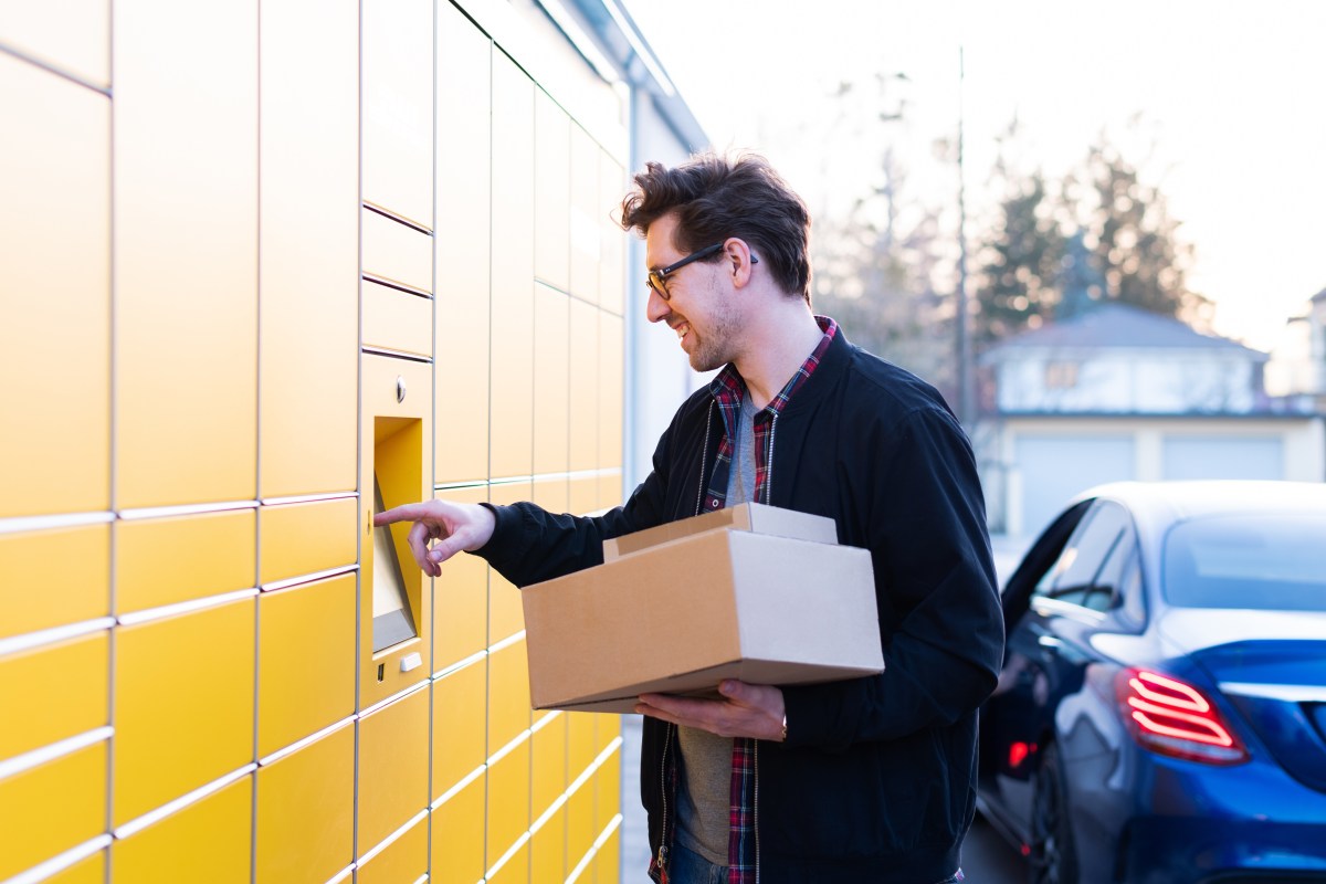 Ein Mann bringt ein Paket zu einer Packstation.