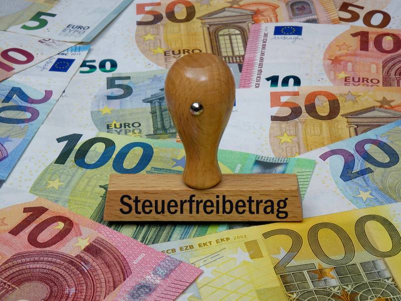 Ein Stempel mit der Aufschrift "Steuerfreibetrag" steht auf Geldscheinen.