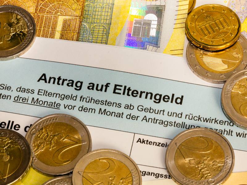 Ein Antrag auf Elterngeld liegt zwischen Geldmünzen