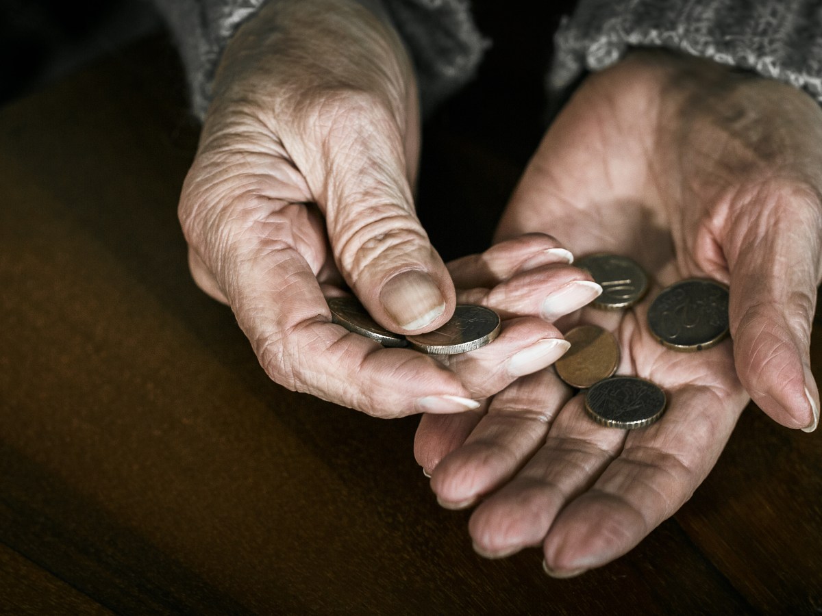 In den Händen einer alten Frau liegen ein paar Münzen.