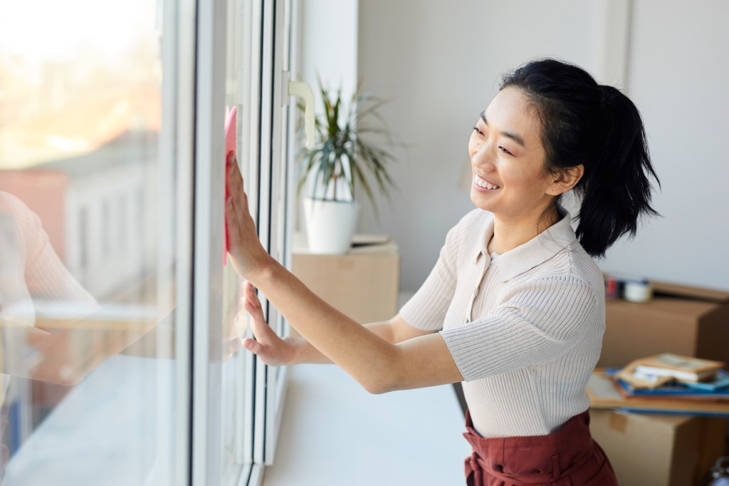 Frau putzt Fenster