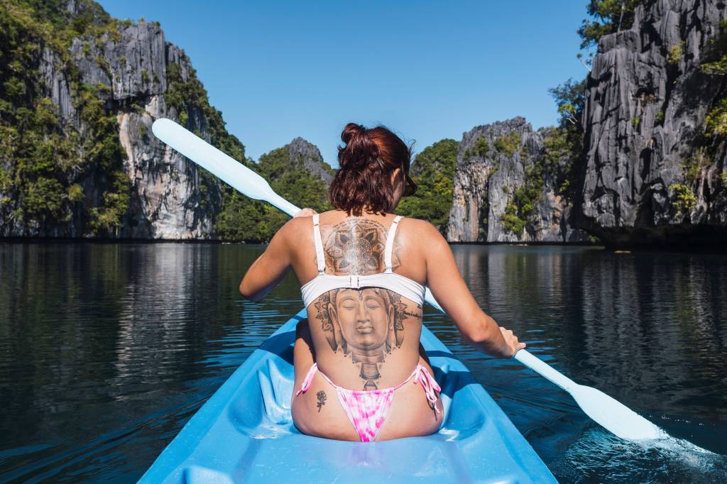 Eine Frau mit weißem Bikini paddelt.