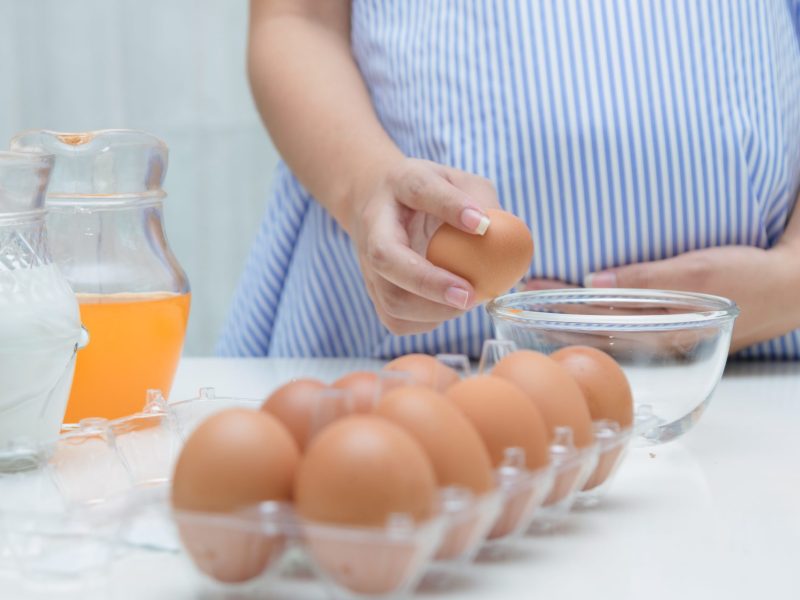 Schwangere Frau Eier aufschlagen