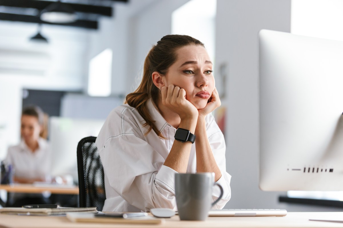 Eine Frau sitzt im Büro vor ihrem Computer und langweilig sich.