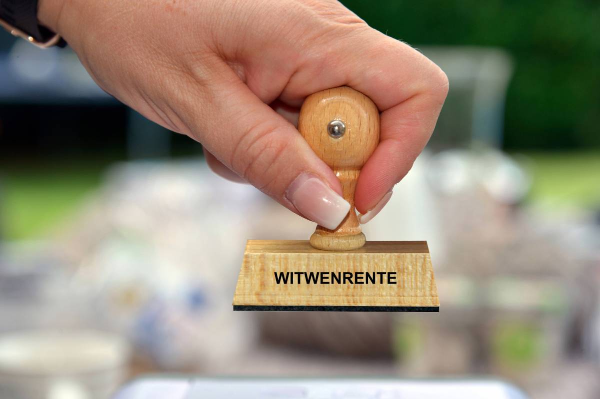 Eine Frau hält einen Stempel mit der Aufschrift "Witwenrente" in der Hand.