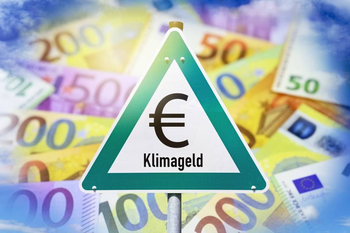 Auf einem Warnschild steht das Wort "Klimageld". Dahinter sind viele Geldscheine.