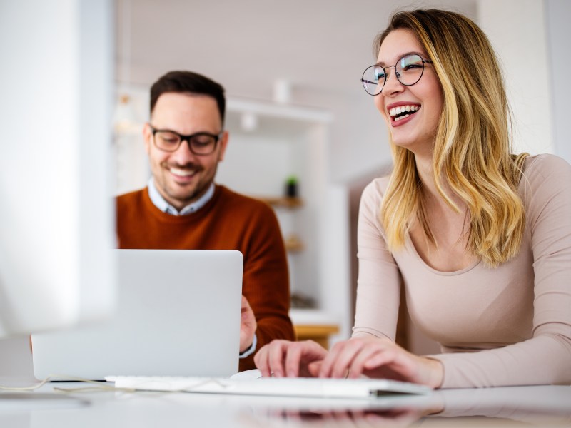 Ein Mann und eine Frau sitzen im Büro am Laptop.