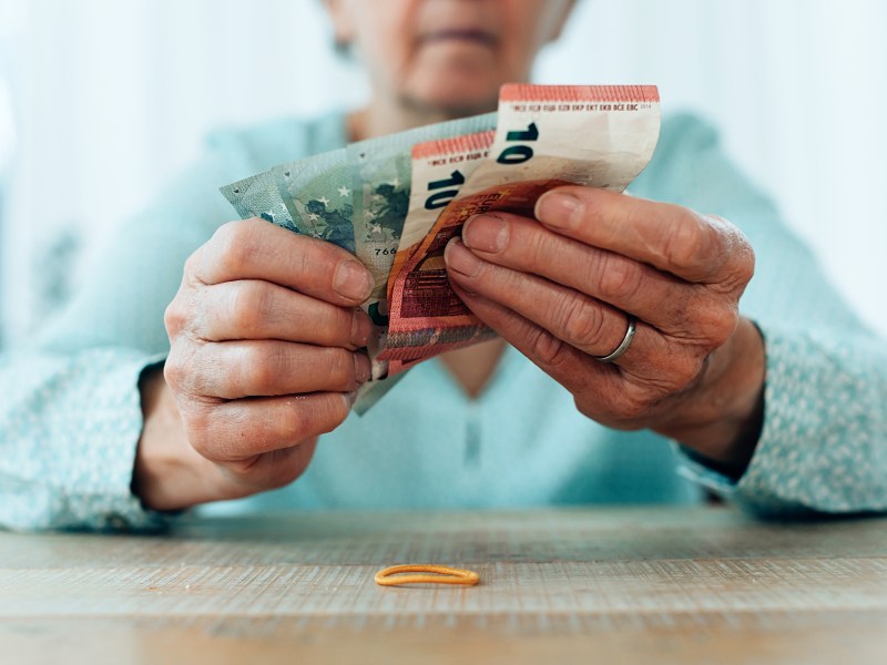 Eine Seniorin hält Geldscheine in der Hand.