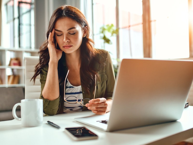 Eine Frau sitzt erschöpft im Büro an ihrem Computer.