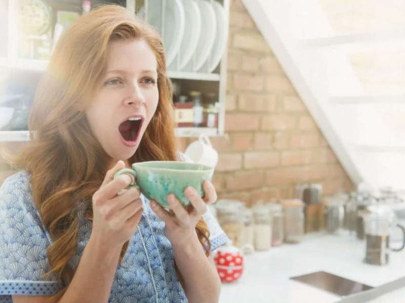 Frau gähnt mit Kaffee